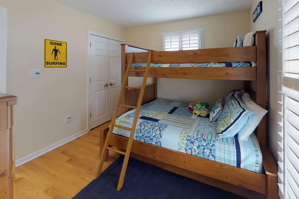 A bright, playful bunk bed nook decorated with stuffed animals and a surfing sign, offering a fun space for kids to play, nap, or engage in creative activities.