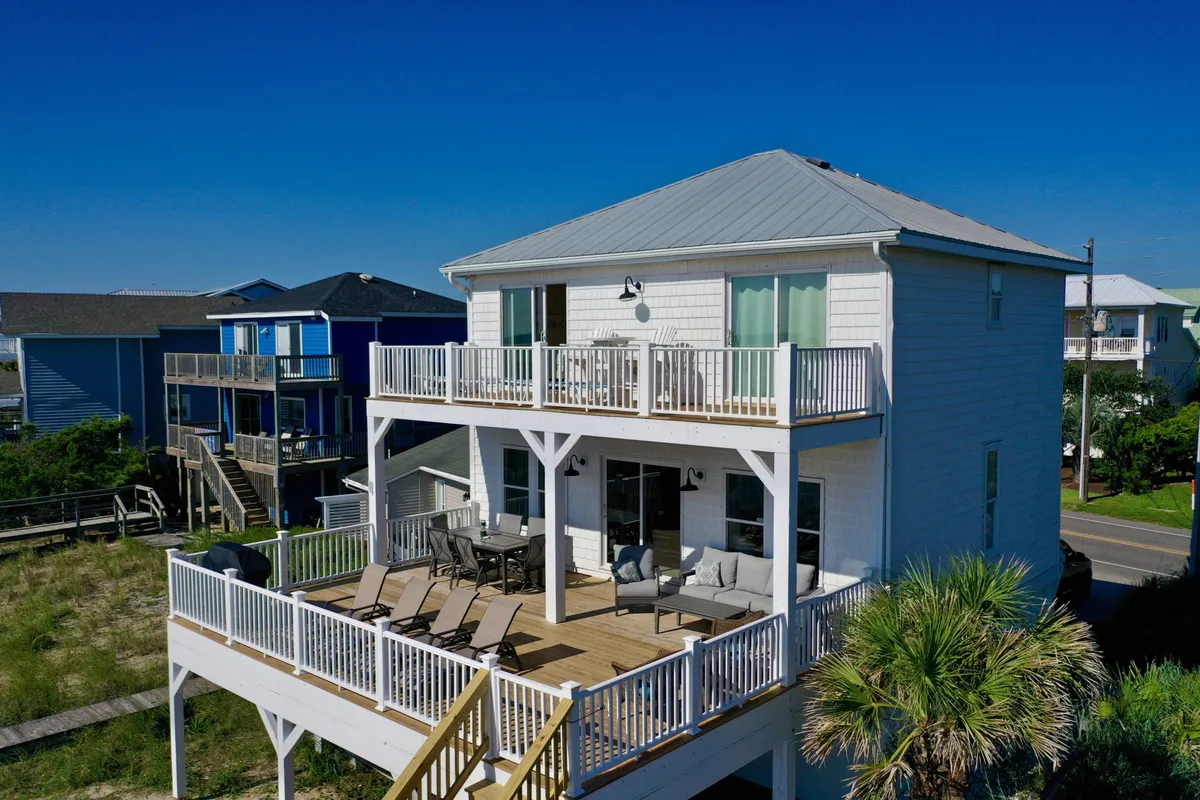 A spacious, sunlit deck with modern architecture and surrounded by greenery, ideal for outdoor games, gatherings, or simply soaking in the fresh air and coastal vibe.